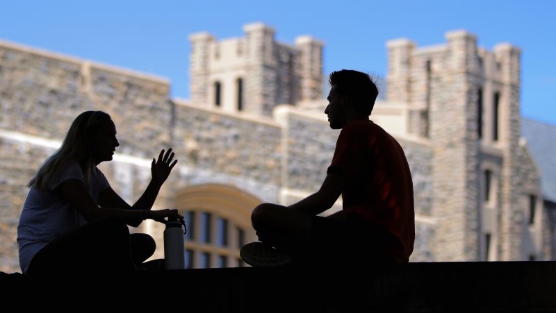 Two students in silhouette, having a conversation. 