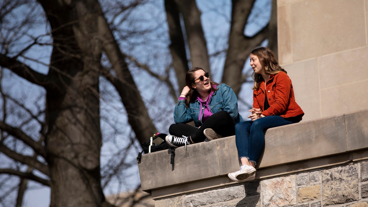 Two students sitting on top of the Chapel laughing and interacting.